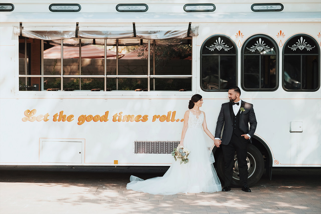 A bridal couple posing in front of the trolley