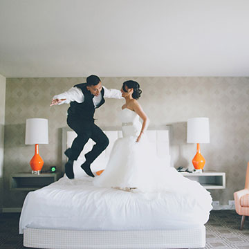 Bride and groom jumping on the bed