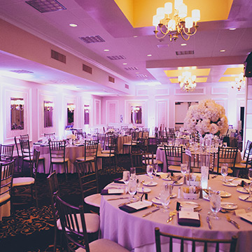 An indoor wedding reception with lavender lighting