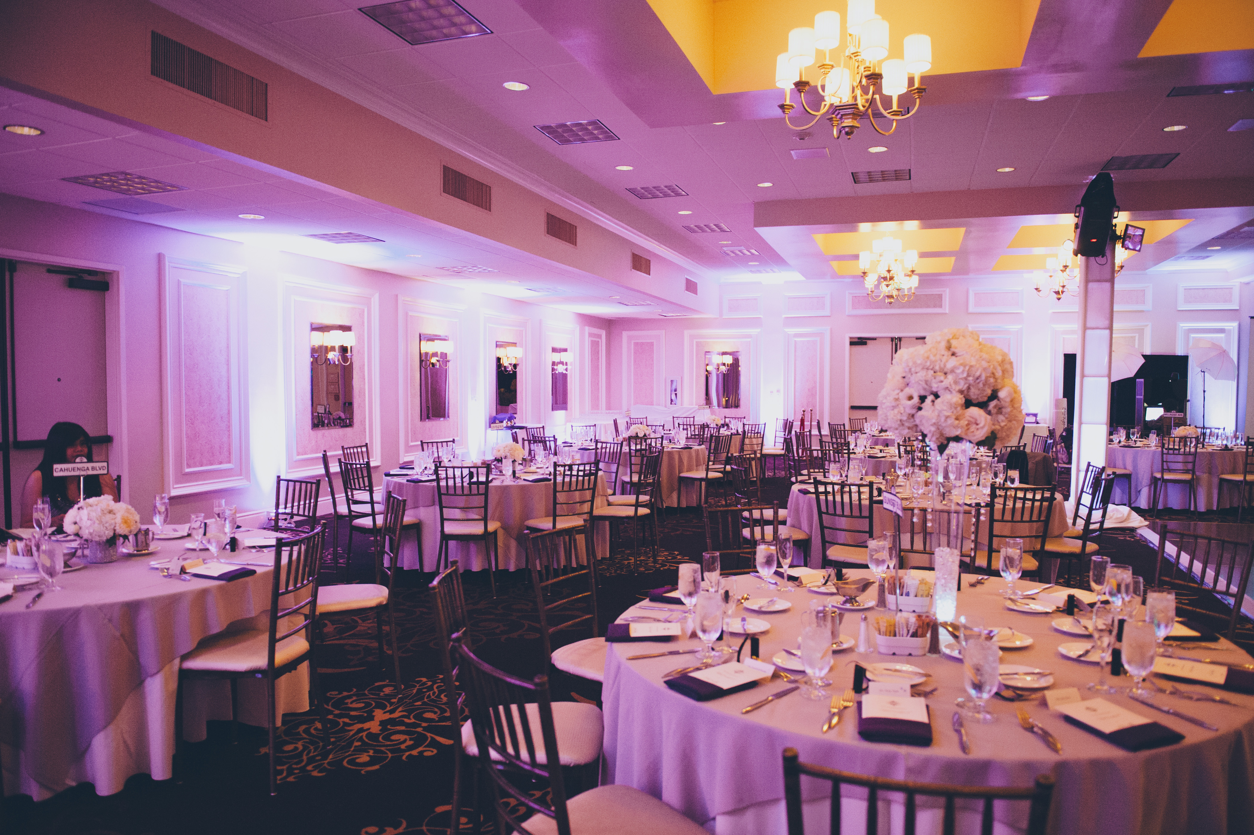 An indoor wedding reception with lavender lighting
